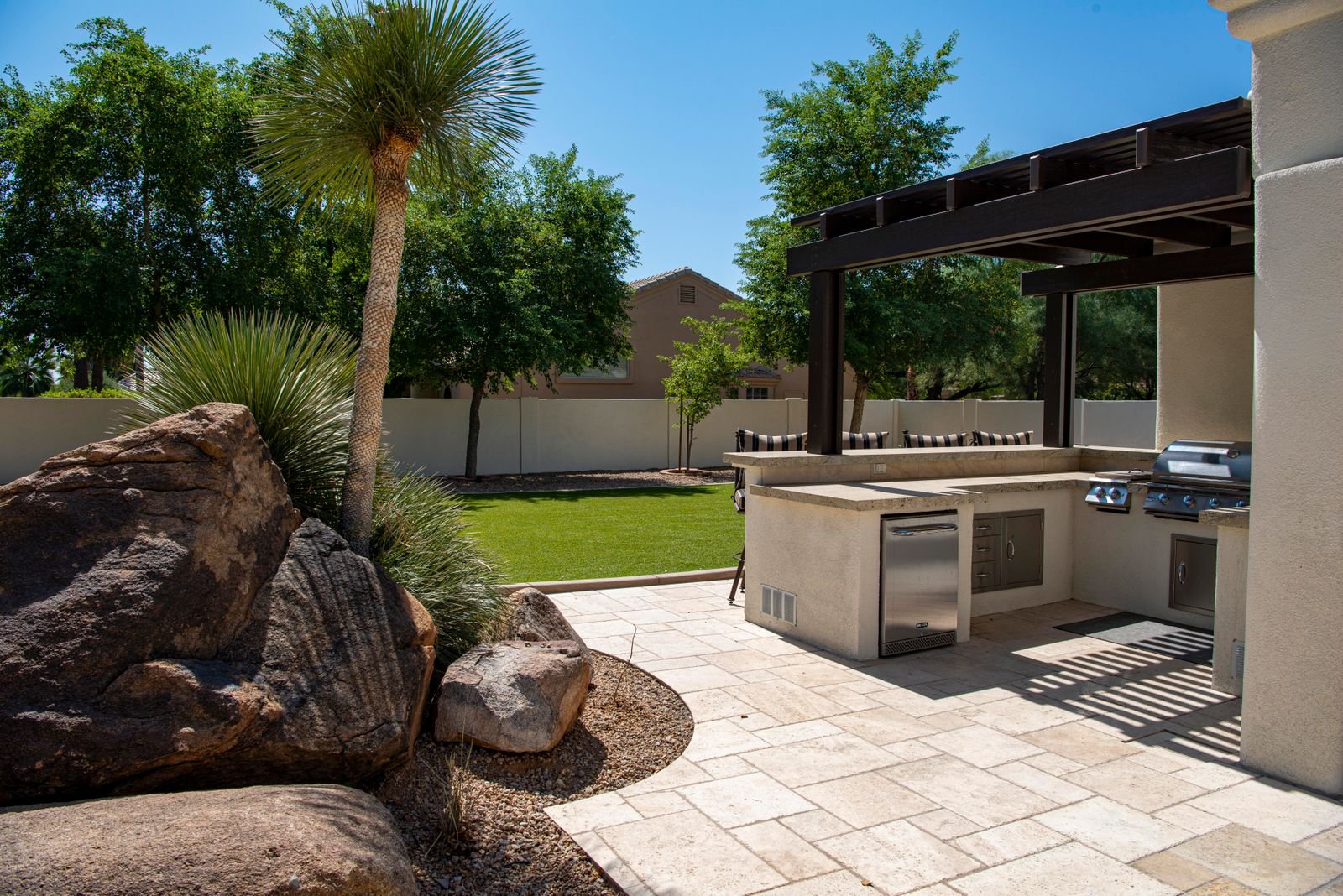 Outdoor kitchen built on a light paver patio in a Florida backyard