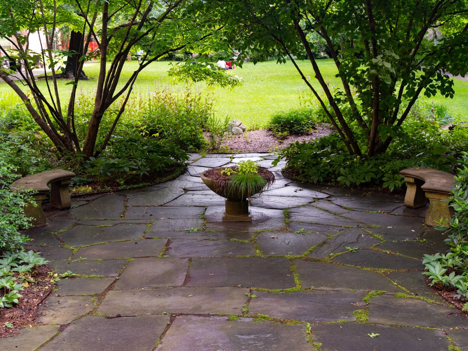 Stone patio with benches in a landscaped garden